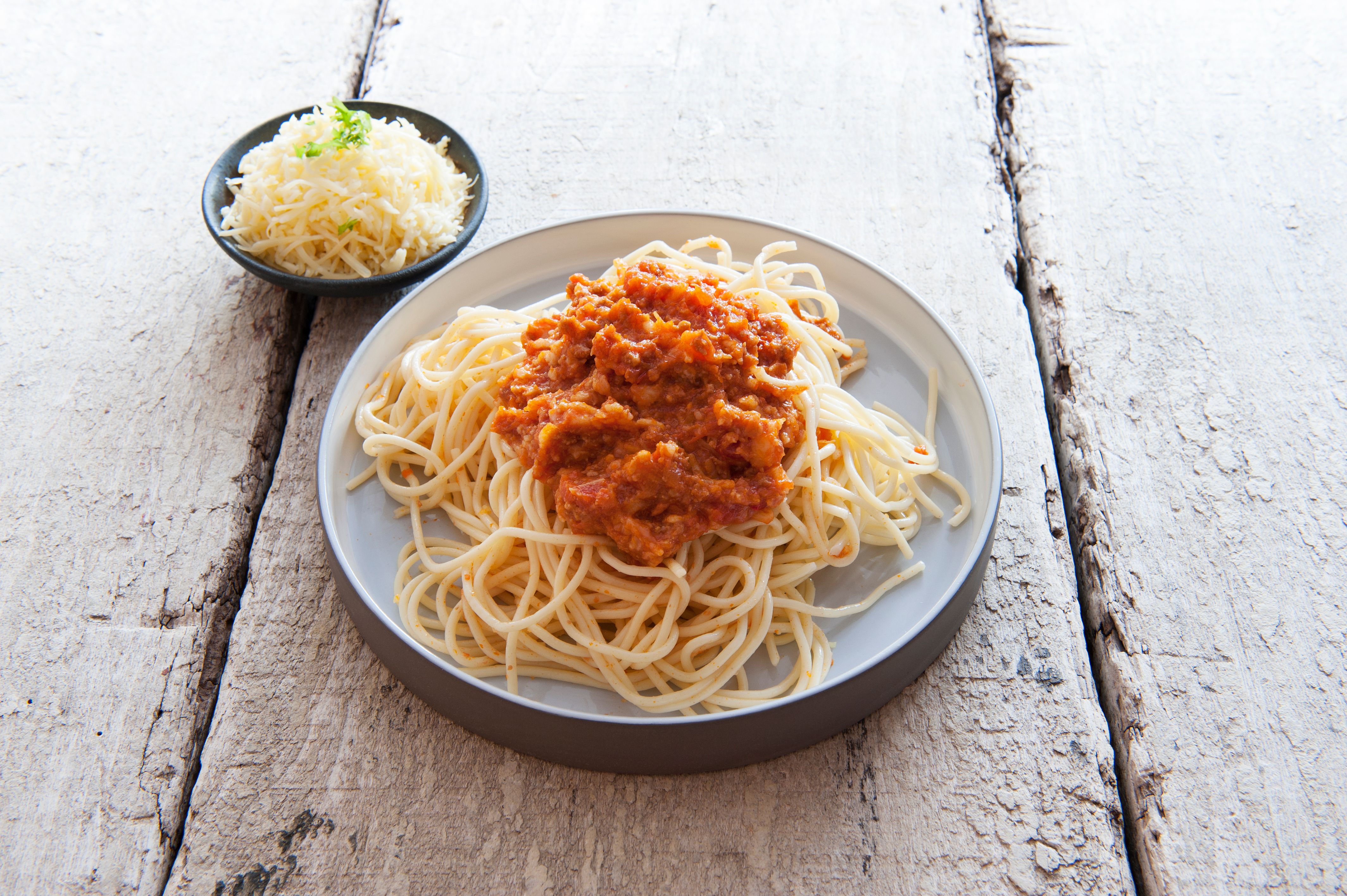 bord met spaghetti, saus en kaas apart