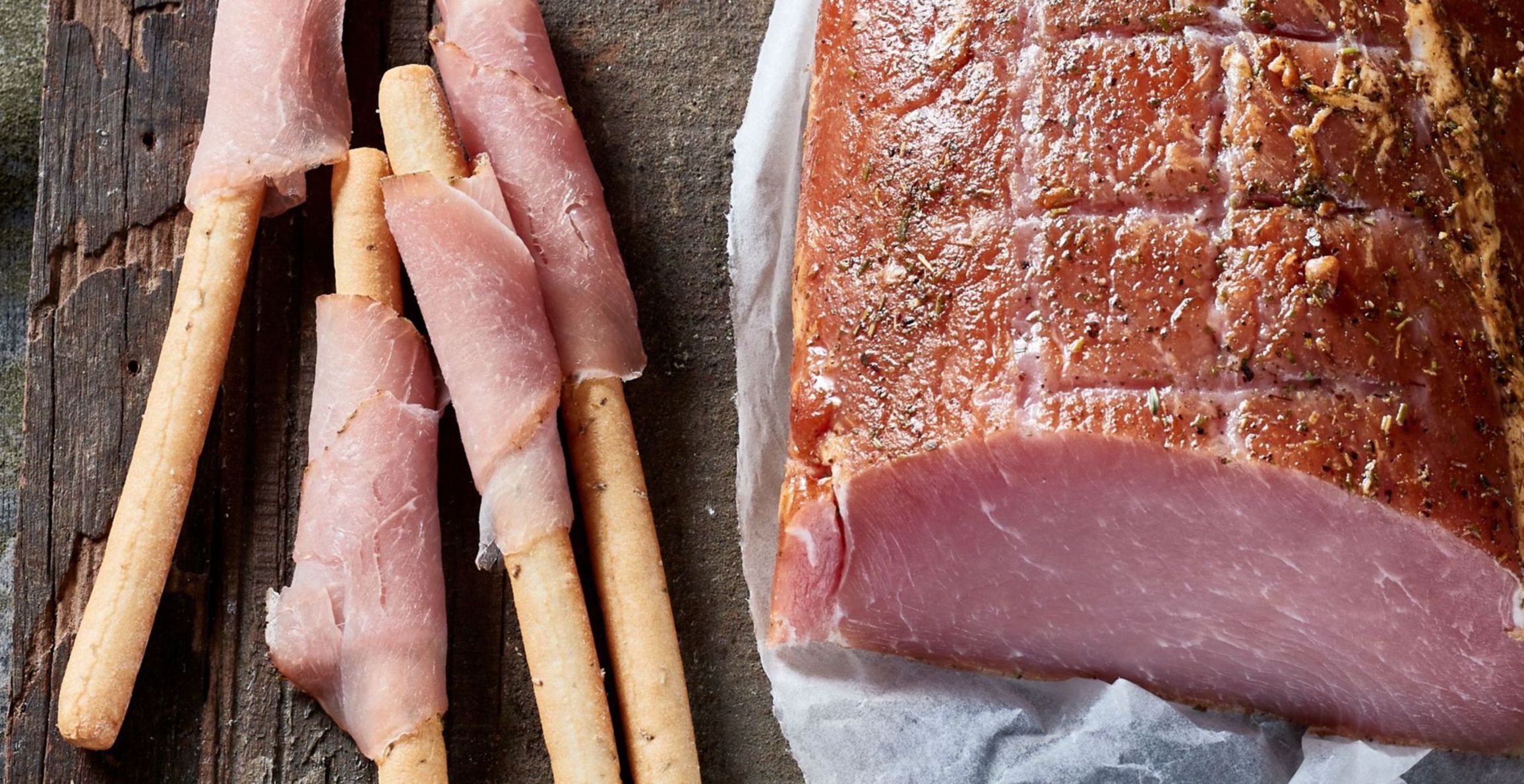 Bacon gerold op soepstengels met bulk product ernaast op houten plank
